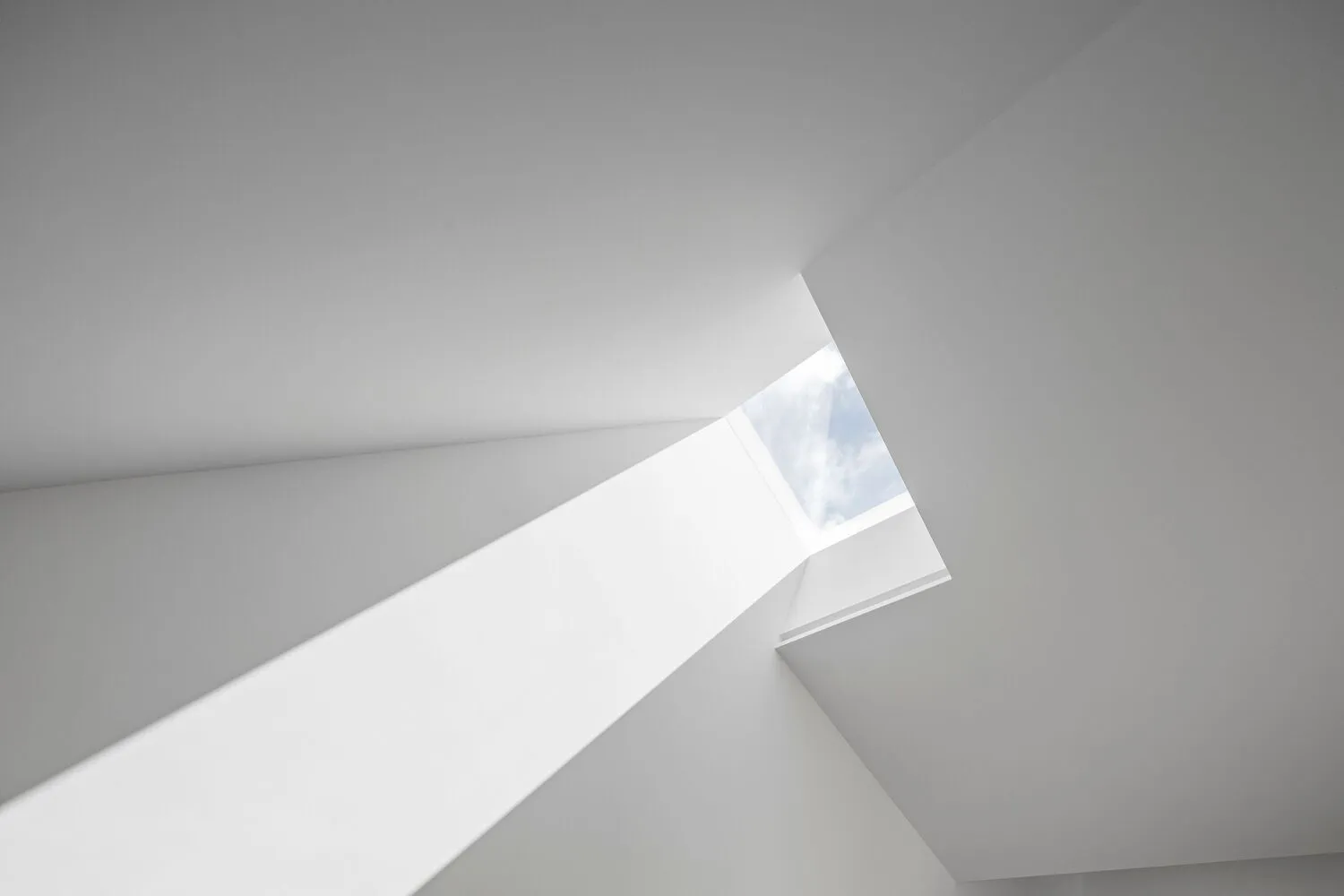 A minimalist white ceiling with a simple window design allowing natural light to illuminate the space.