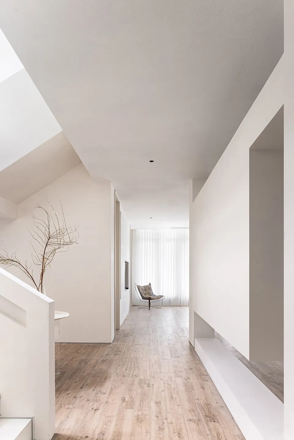 Modern minimalist house with white interior featuring wooden flooring, concrete walls, and glass elements.