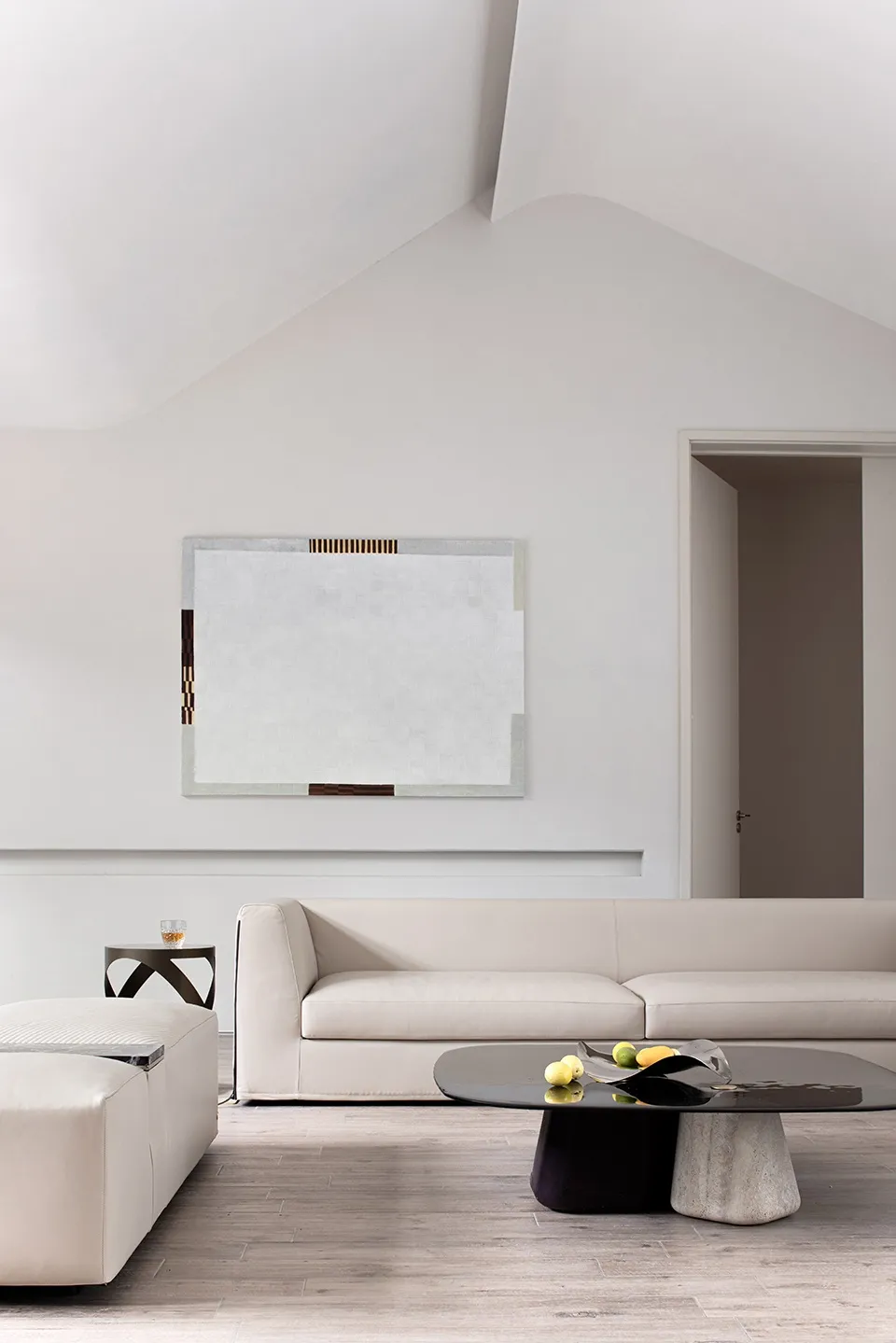 A modern minimalist living room with a minimalist sofa, abstract art, wooden floor, and geometric coffee table.