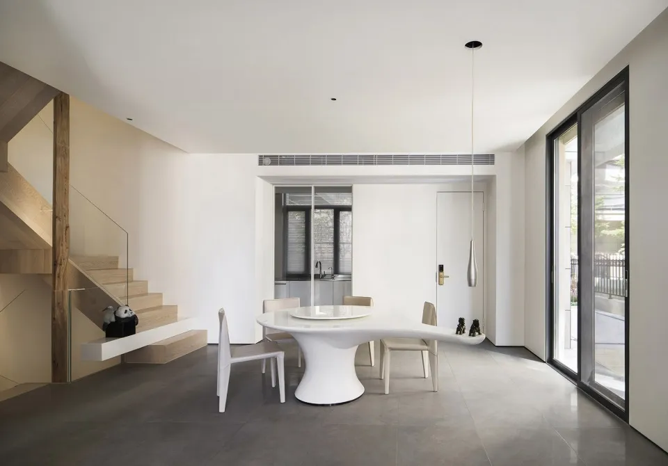 A modern dining room features a white table and chairs, with a sleek, minimalist design.