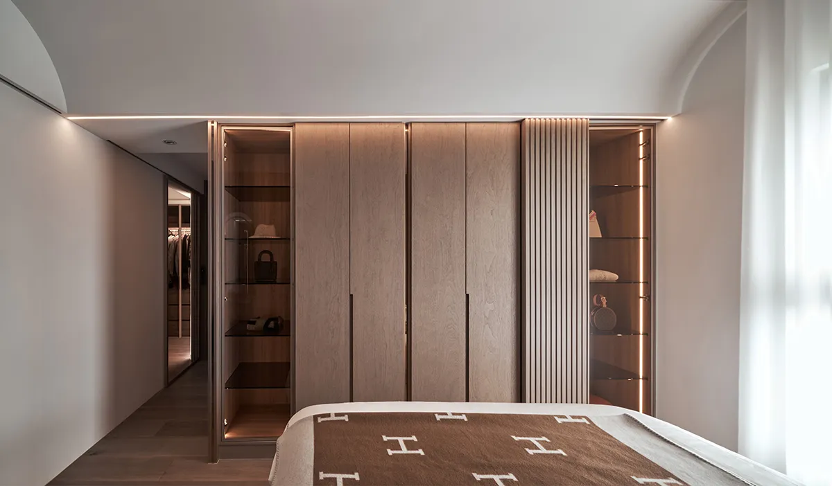 Modern wooden closet with glass-front cabinet doors and built-in shelves.