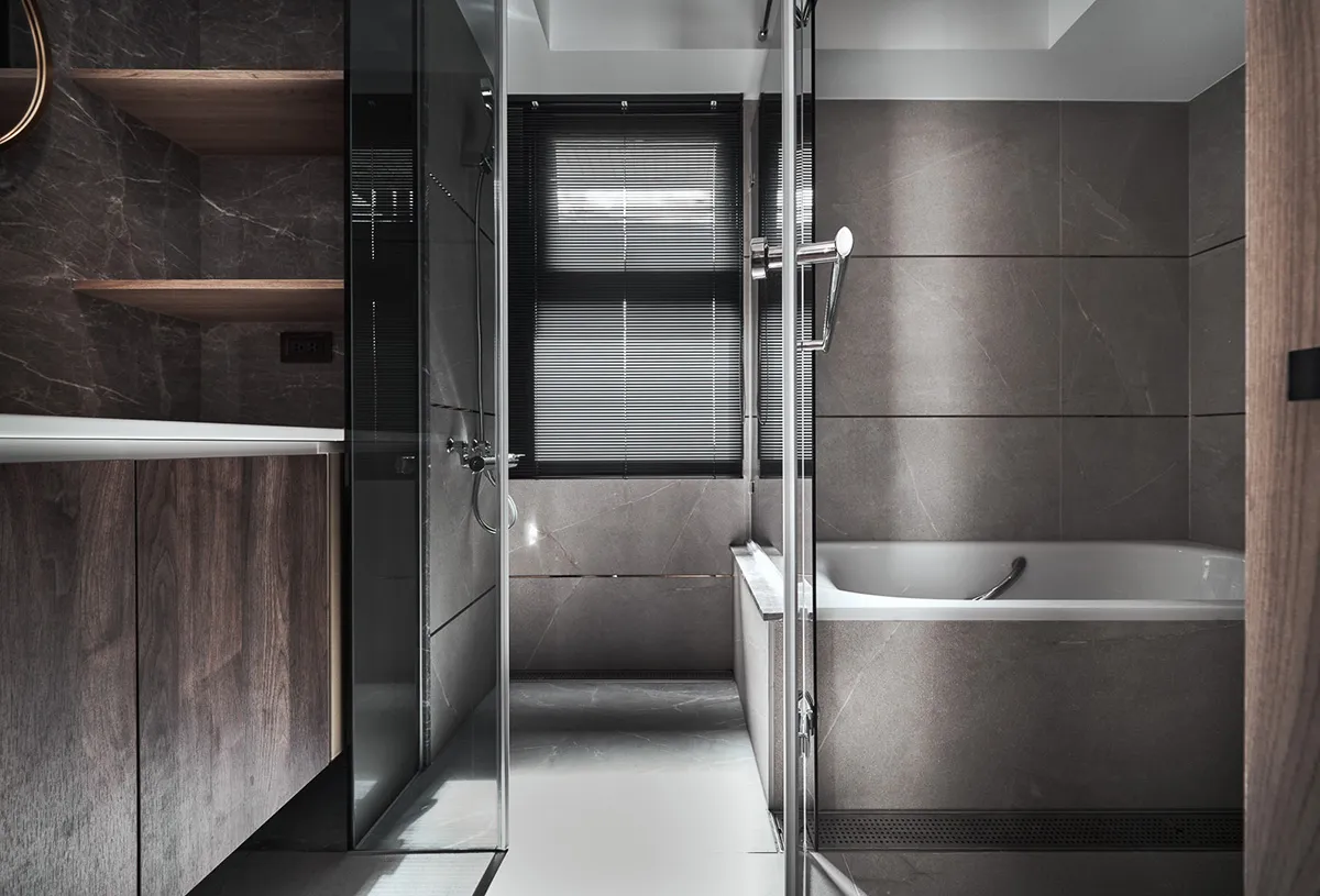 Modern dark bathroom with concrete tiles and a glass shower enclosure.