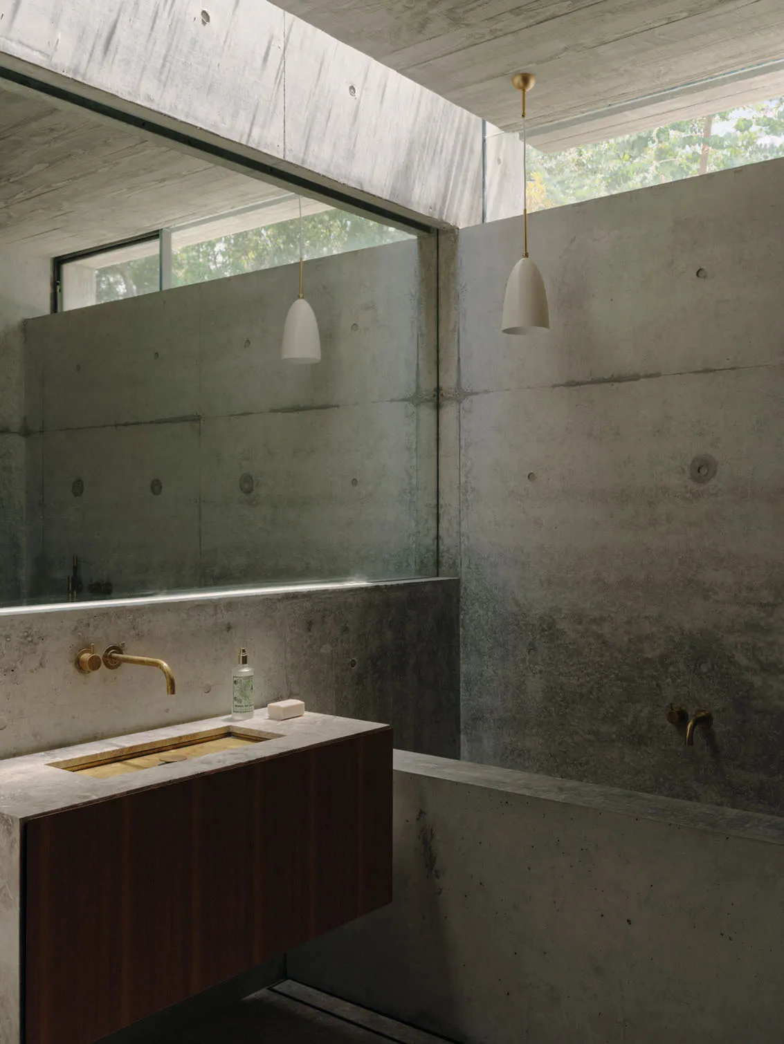 Industrial-style bathroom with concrete walls and floor, featuring a minimalist sink and metal fixtures.