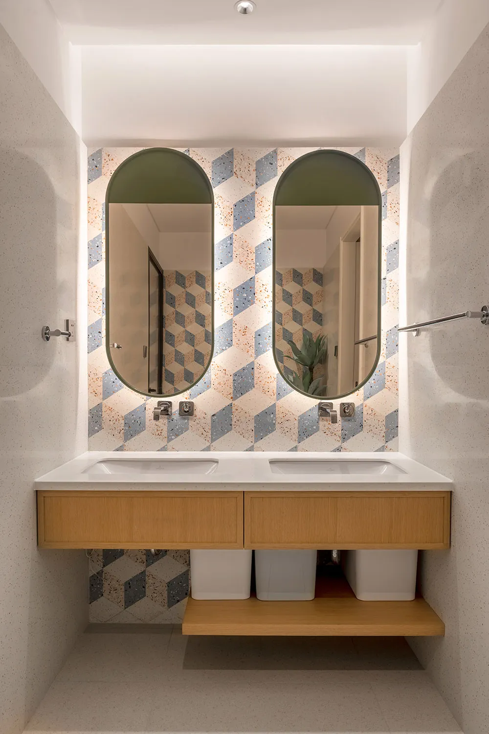 Modern bathroom with white terrazzo tiles and floating wooden vanity with dual sinks and mirrors.