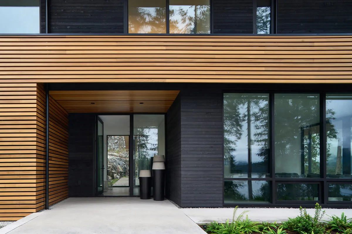 Modern house exterior with wooden cladding and large glass windows.