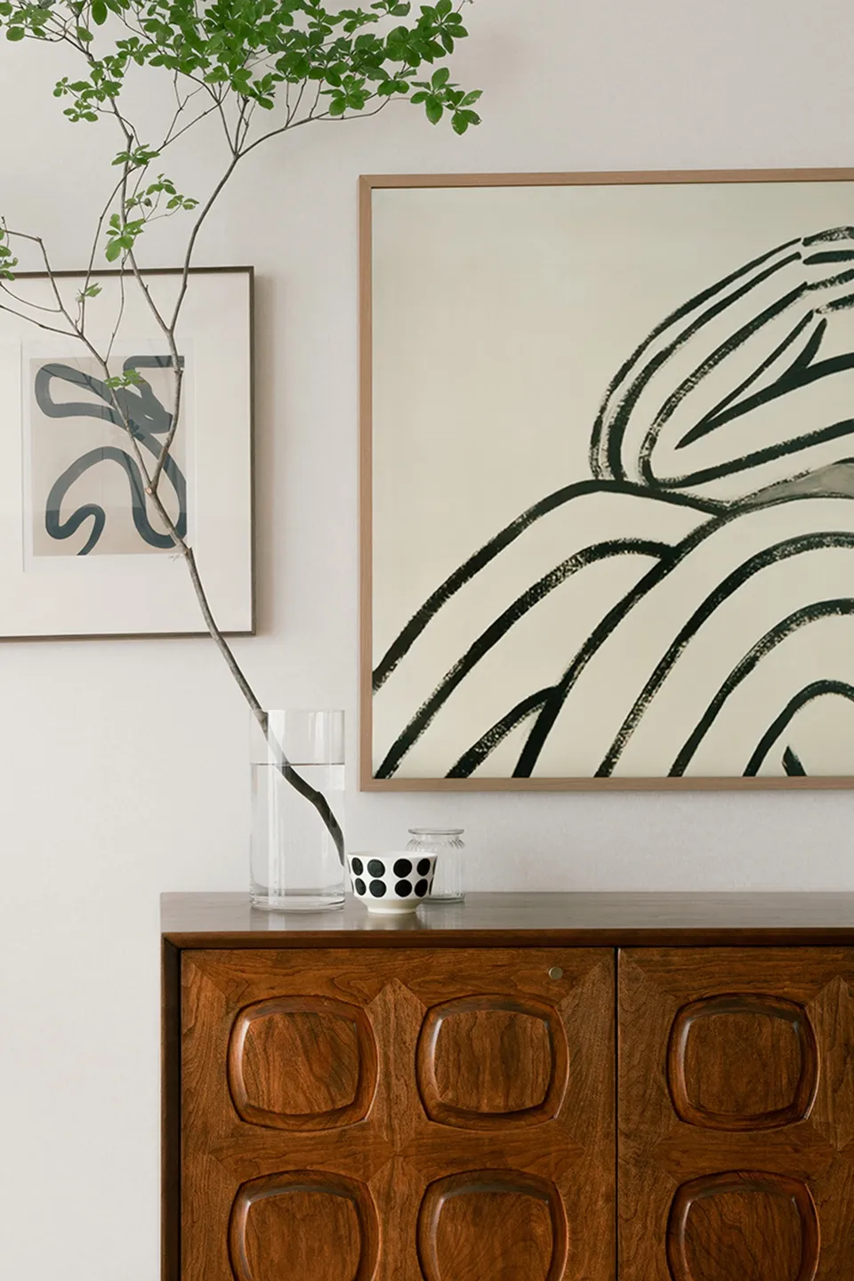 A modern interior showcasing an abstract artwork with black lines and a wooden cabinet.