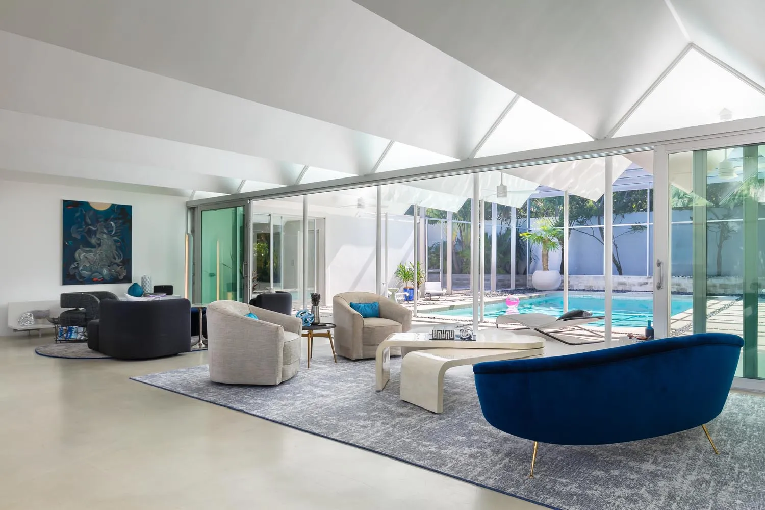 A modern living room featuring glass furniture and a large glass wall with a view of a pool.