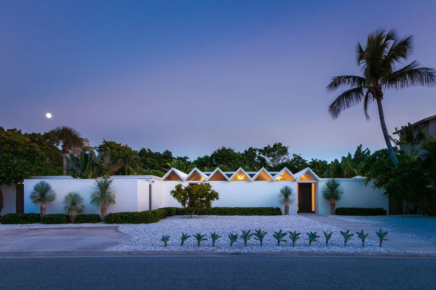 A modern residential exterior with concrete walls and white gravel pathway.