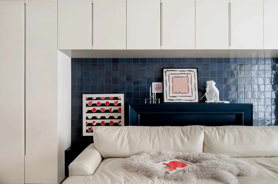A modern living room with a blue tile backdrop and a white sectional sofa.