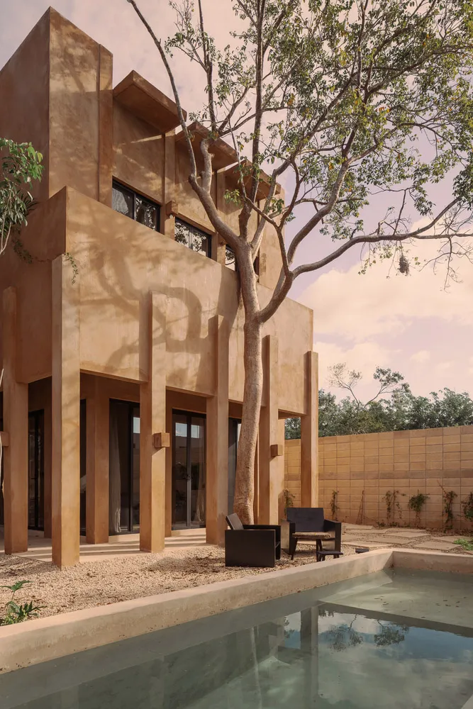 Modern house exterior with concrete walls and a tree in the yard.