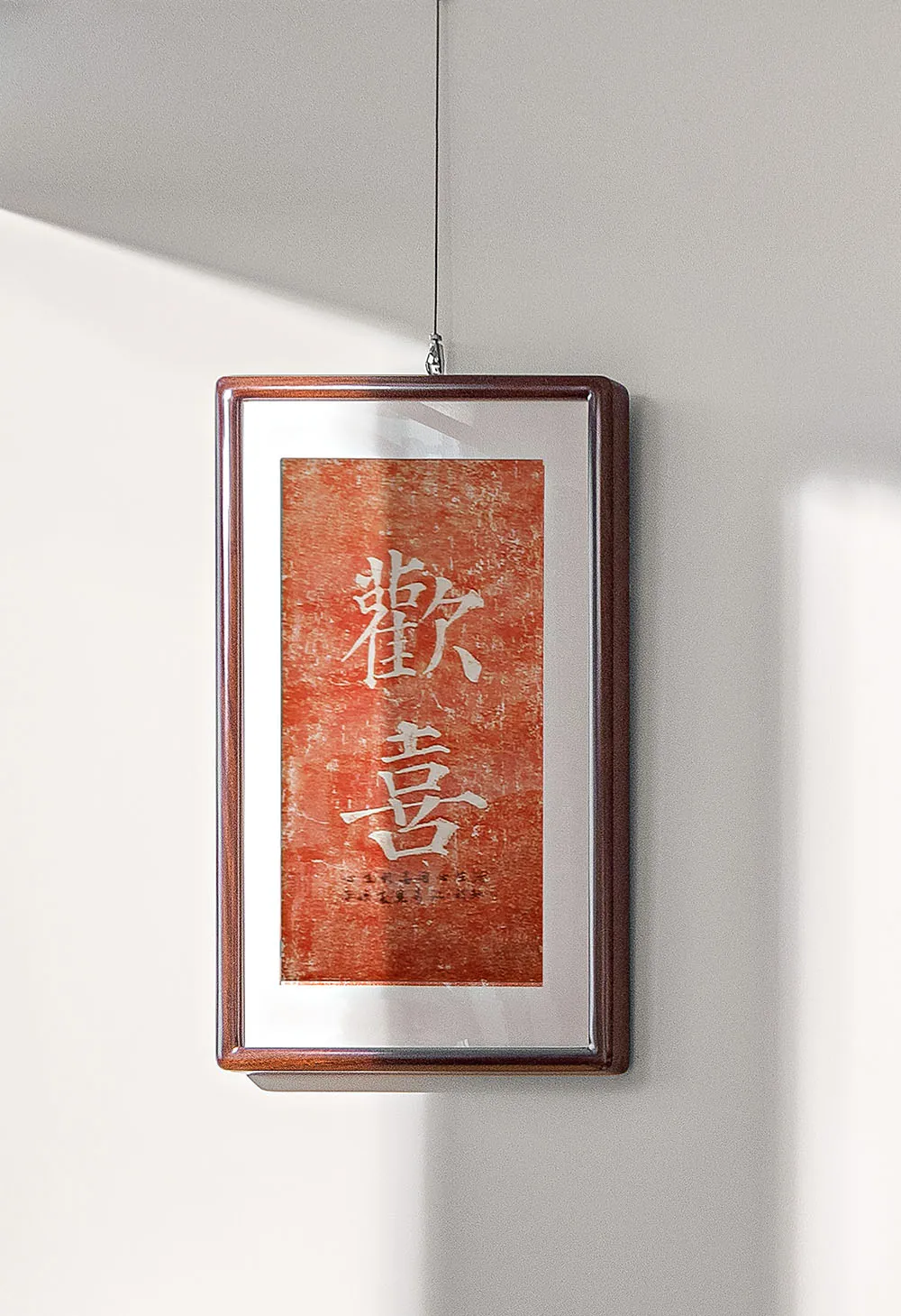 A framed piece of calligraphy art hanging on a white wall.