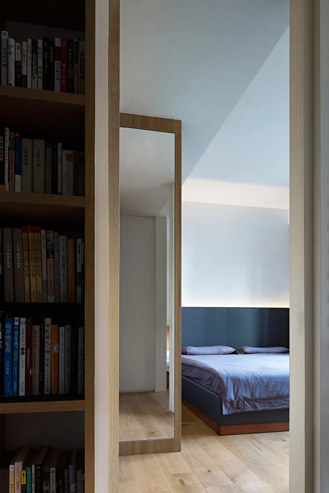 A minimalist bedroom with wooden furniture and a blue bedspread.