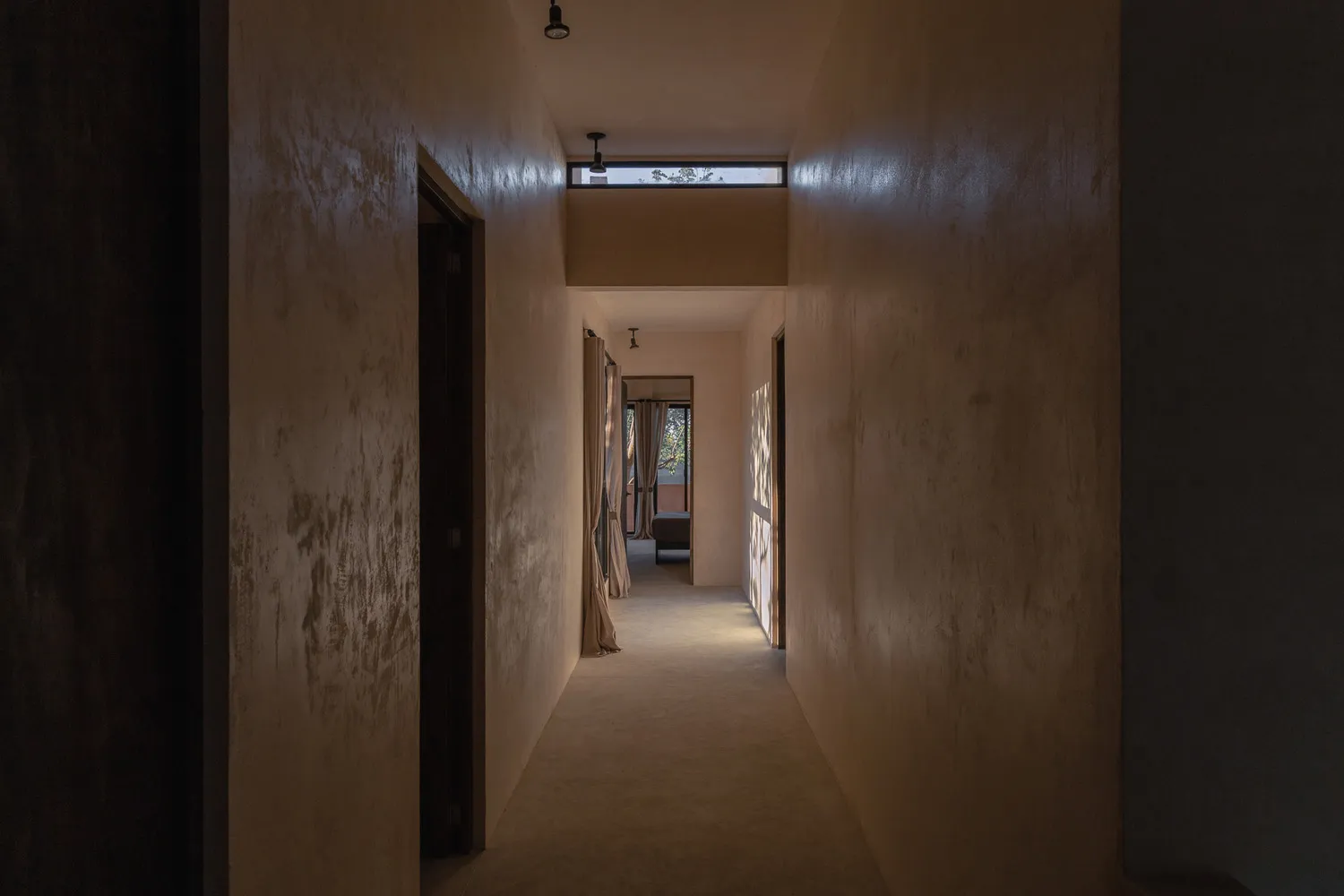 An empty minimalist hallway with concrete walls and a long, light-filled corridor.
