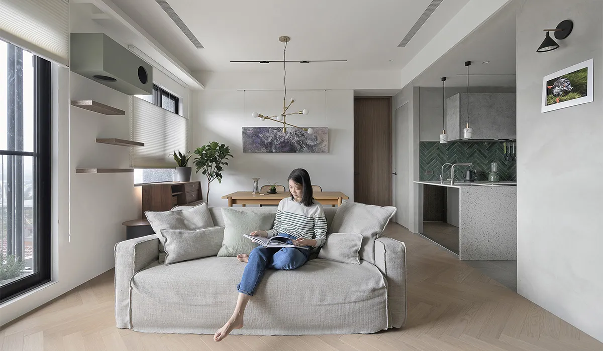 A modern living room with a concrete floor, wood furniture, and a fabric sofa.