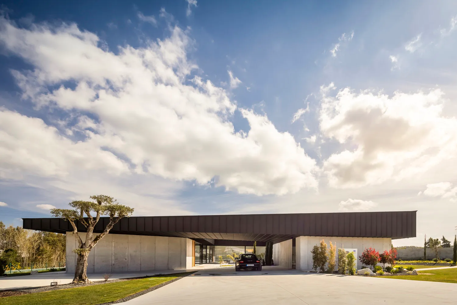 A modern house with a concrete exterior under a blue sky with white clouds.