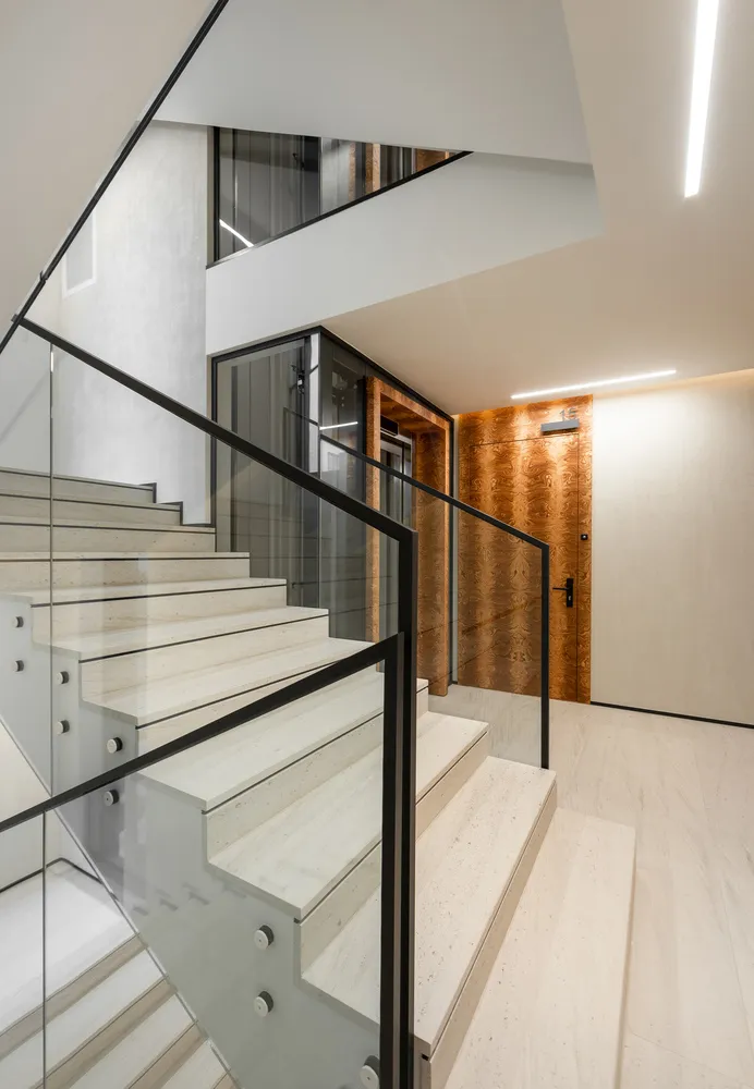 A modern interior design featuring a staircase with concrete steps and glass railings.