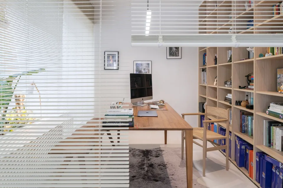 A modern minimalist office space featuring a wooden desk and glass shelving.