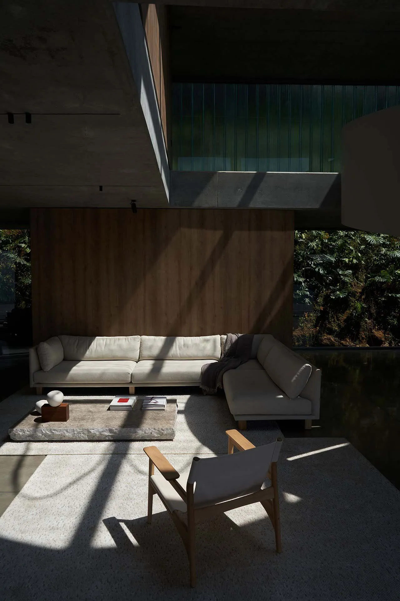 Contemporary living room with concrete walls, a minimalist sofa, and a stone coffee table.