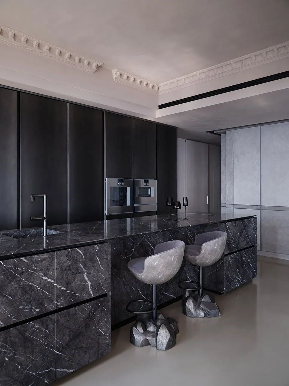Modern kitchen with marble countertops, black cabinetry, and minimalist design.