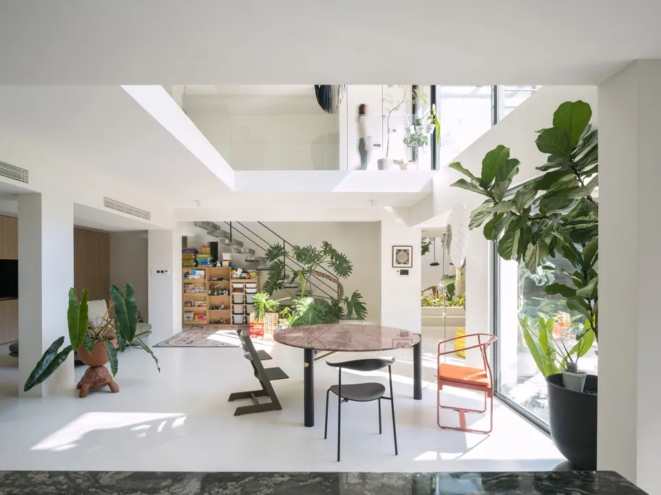 A modern, minimalist living room with concrete flooring, industrial styling, and a mix of natural and artificial greenery.
