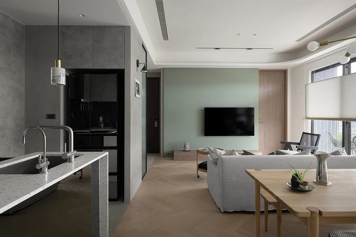 A modern living room featuring concrete walls, wooden flooring, and fabric couches.