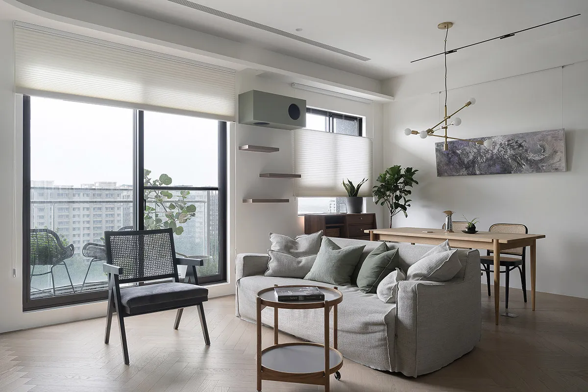A modern living room with a gray sofa, wooden table, and minimalist decor.