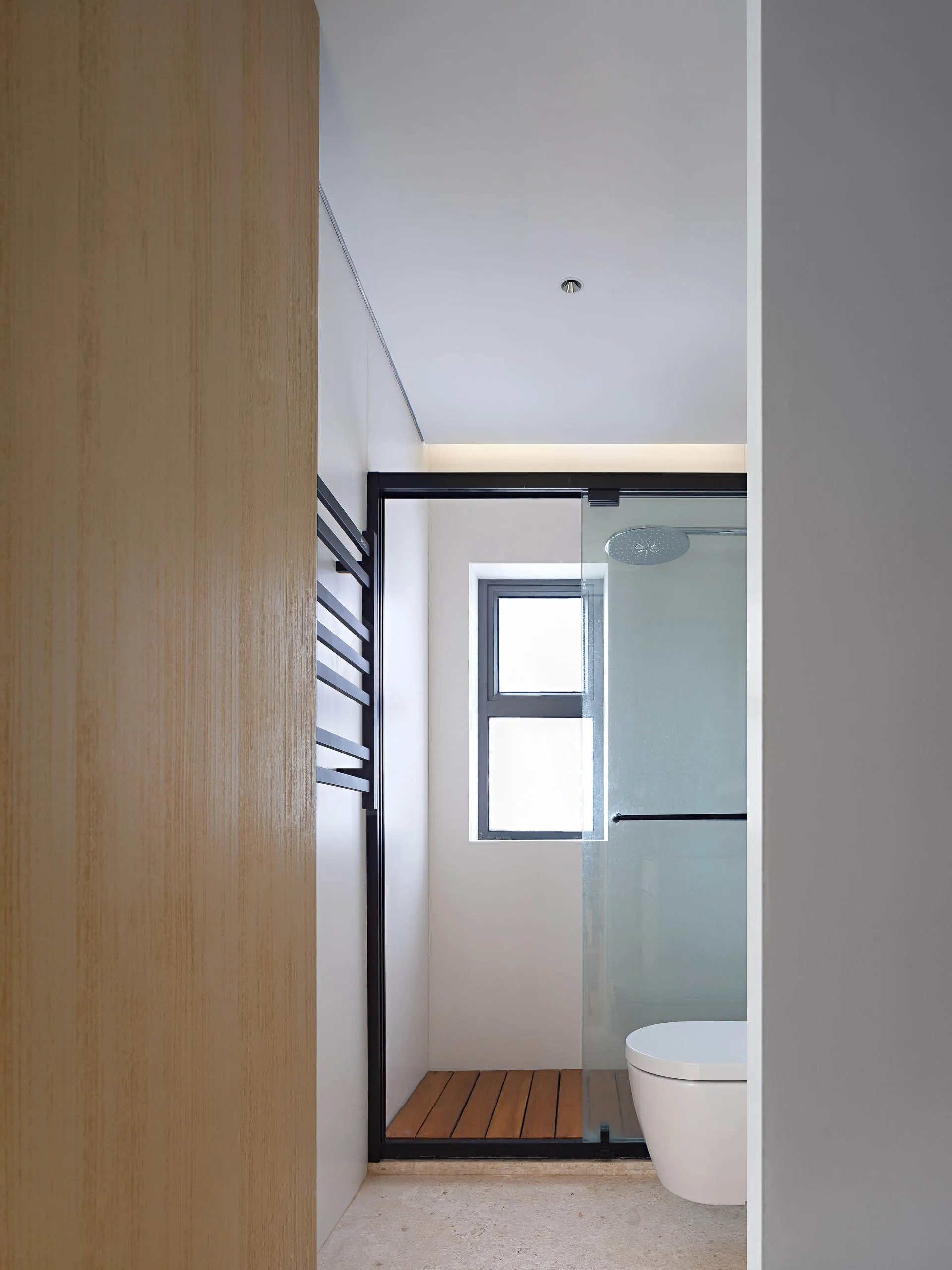 Modern minimalist bathroom with glass shower enclosure and wooden accents