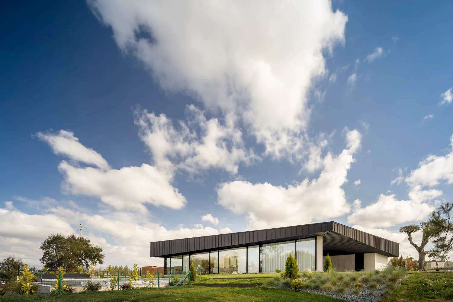A modern building with a glass and steel exterior under a blue sky with clouds.