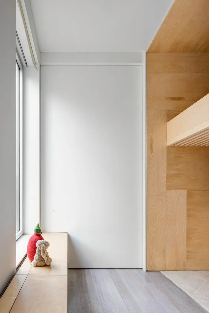 A minimalistic bedroom featuring wooden paneling and a large window with natural light.