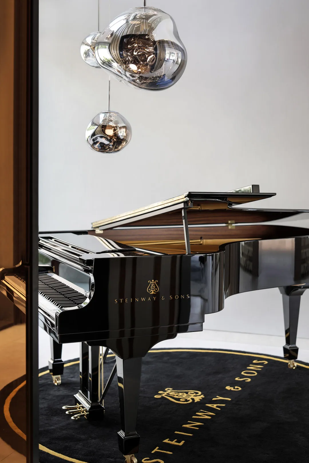 A modern music room featuring a black Steinway & Sons piano, complemented by contemporary pendant lights.