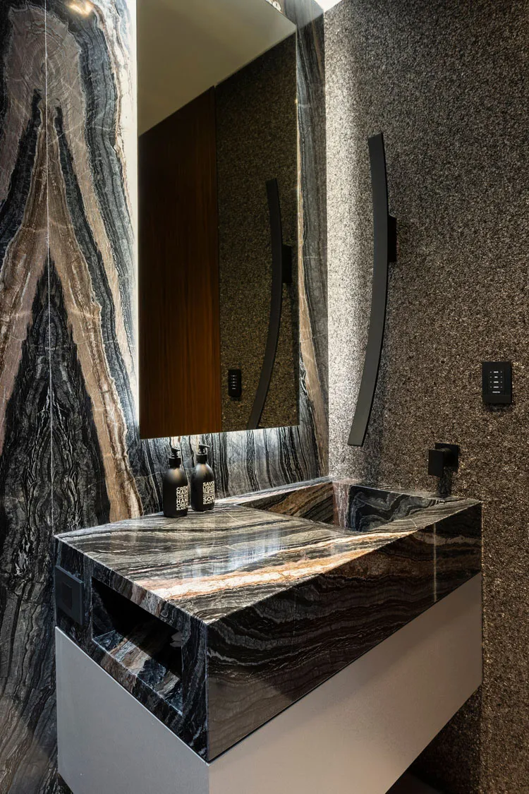 A luxurious modern bathroom with a marble sink, mirror, and walls.