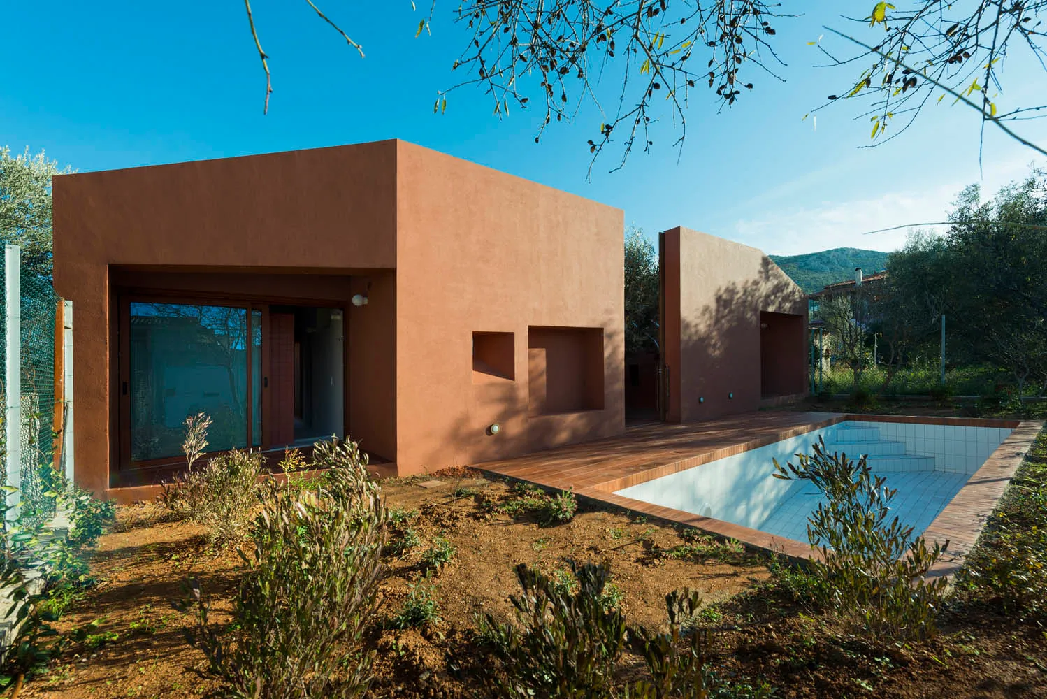 A modern residential building with a pool, made of terrazzo and featuring a wooden deck.