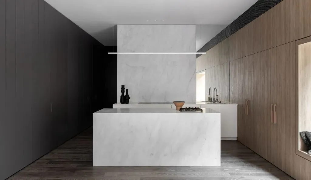 Modern residential kitchen featuring a minimalist design with a white marble countertop and backsplash.