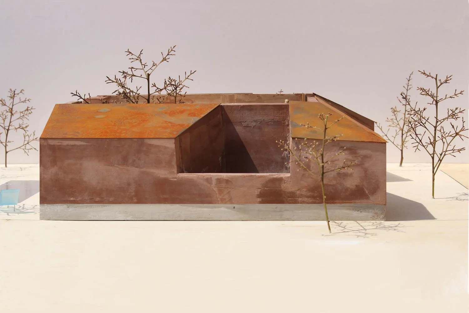 Model of a building with a metallic roof and minimalist design.