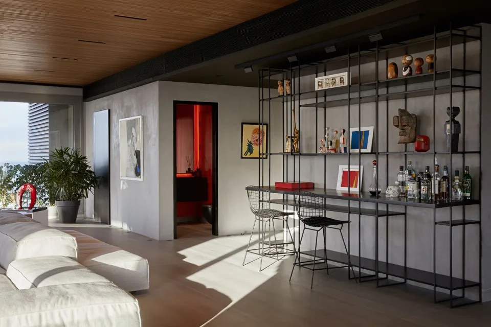 A modern living room with a concrete wall, a bar counter, and a lounge area.
