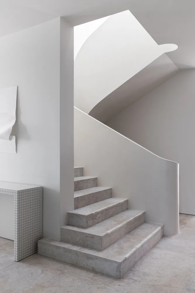 A modern, minimalist concrete staircase with a sleek, curved design.
