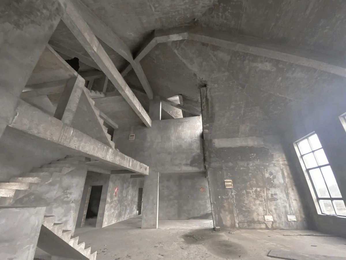 Unfinished interior space with concrete walls and stairs in a building under construction or renovation.