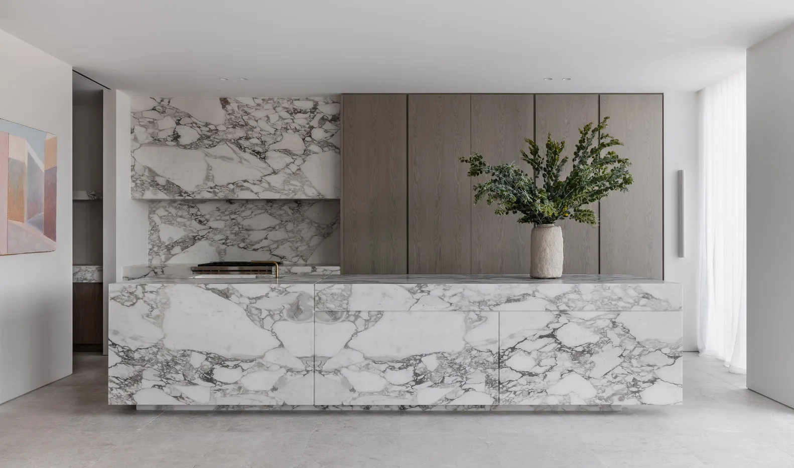 A modern minimalist kitchen featuring marble countertops and cabinets.