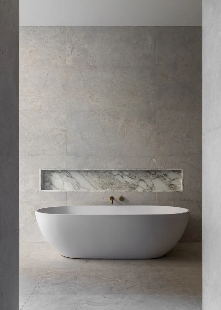 Modern minimalist bathroom featuring a freestanding bathtub with marble accents and a minimalist design.