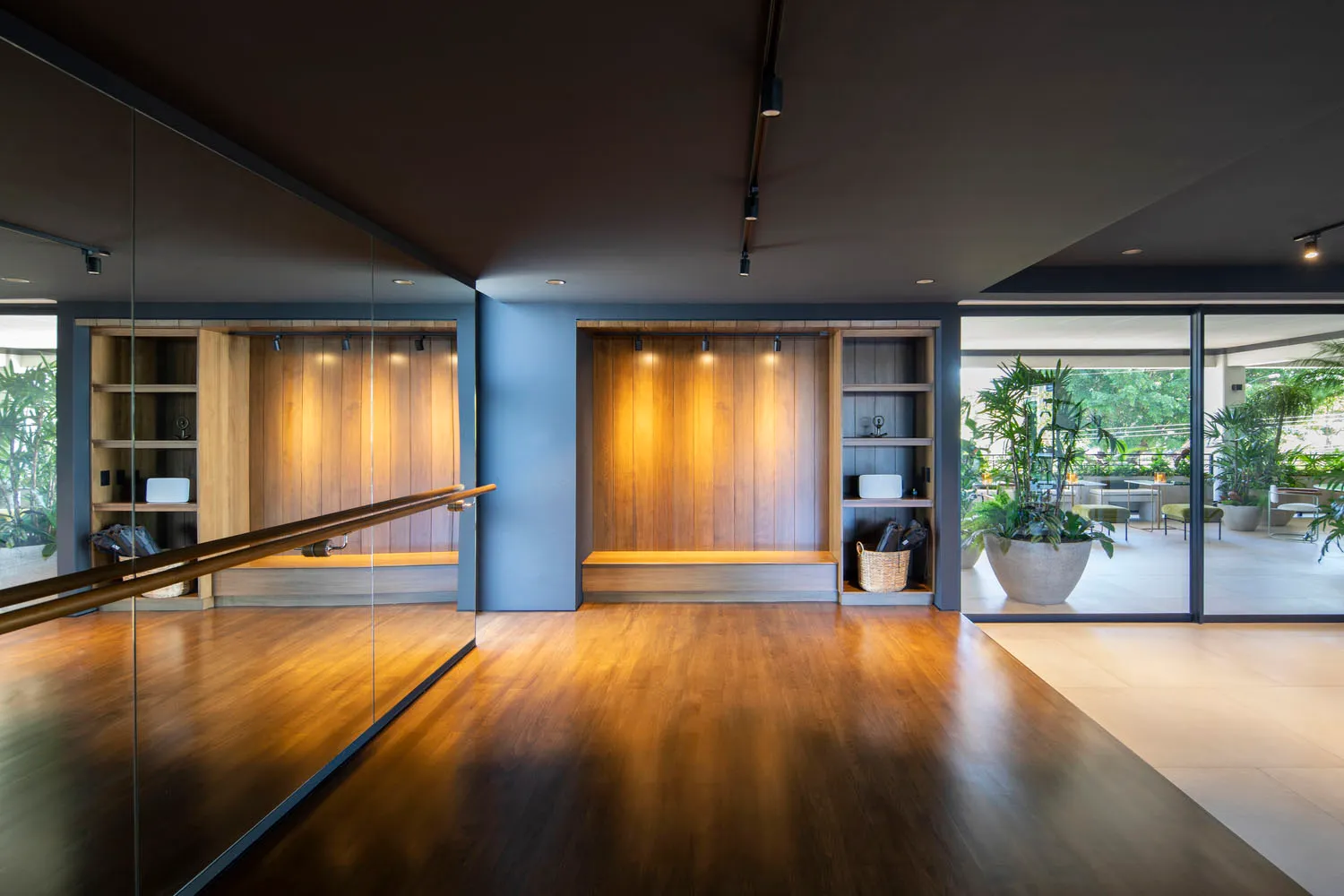 A minimalist fitness studio featuring wooden flooring, glass partitions, and concrete accents.