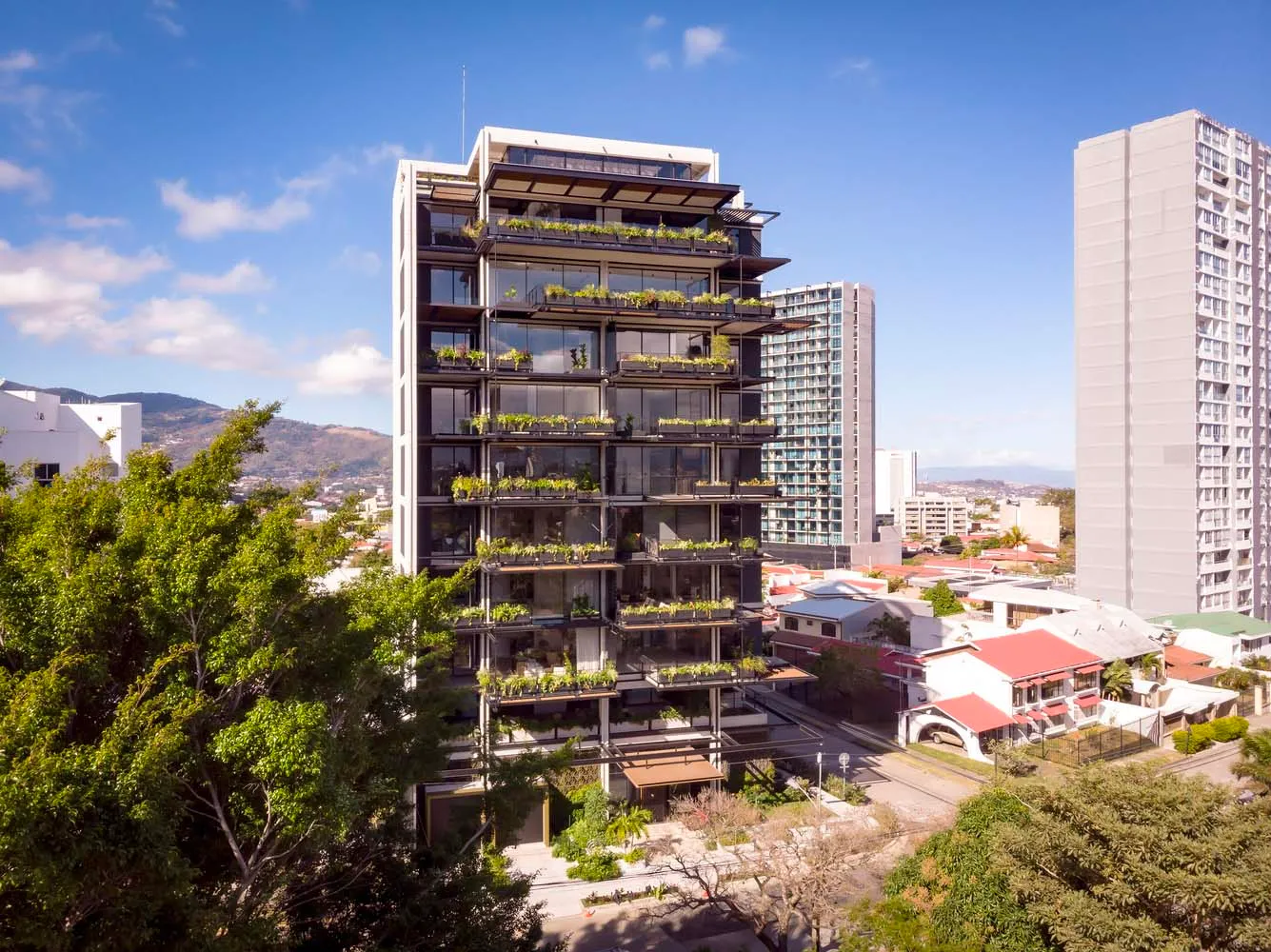 Modern apartment building with glass façade and green plants on balconies