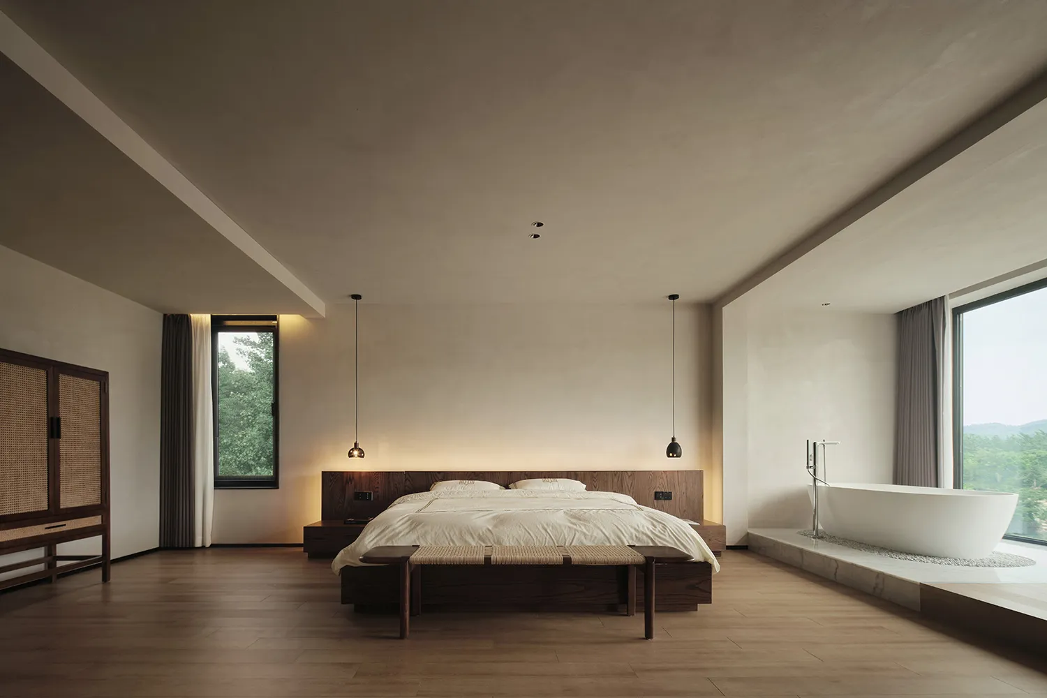 Modern minimalist bedroom with a wooden bed frame, white linens, and marble flooring, featuring natural light and views of gr