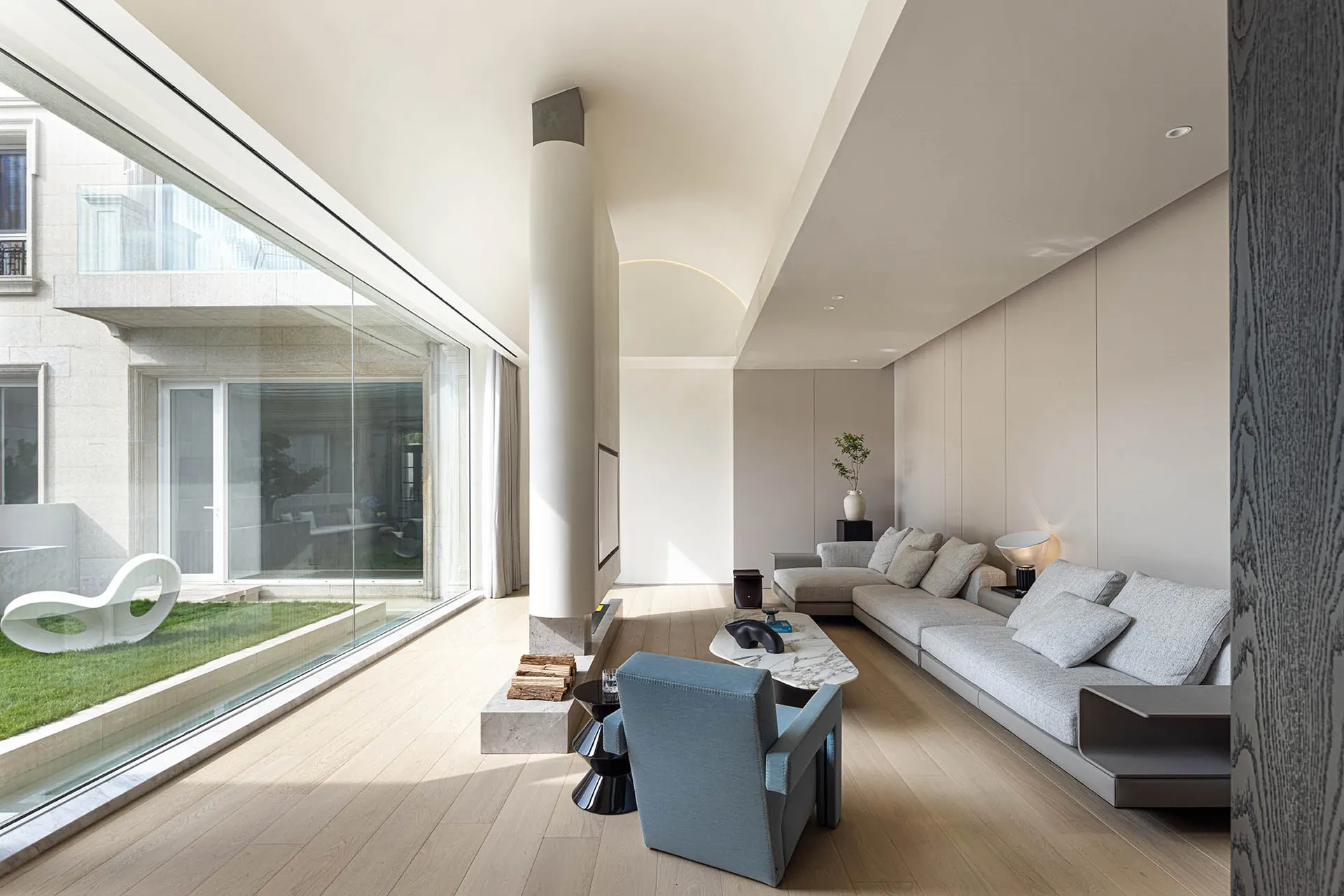 A modern living room featuring a large glass wall, a wooden floor, and a comfortable sofa.