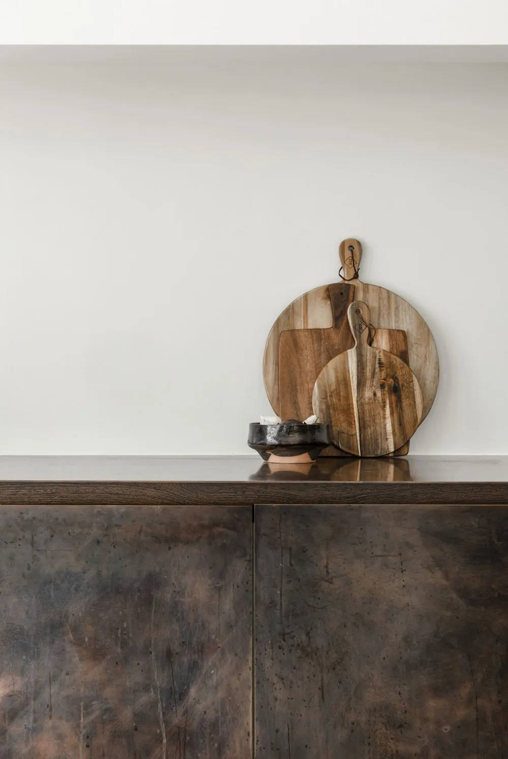 A modern kitchen with a wooden board on a dark, textured countertop.
