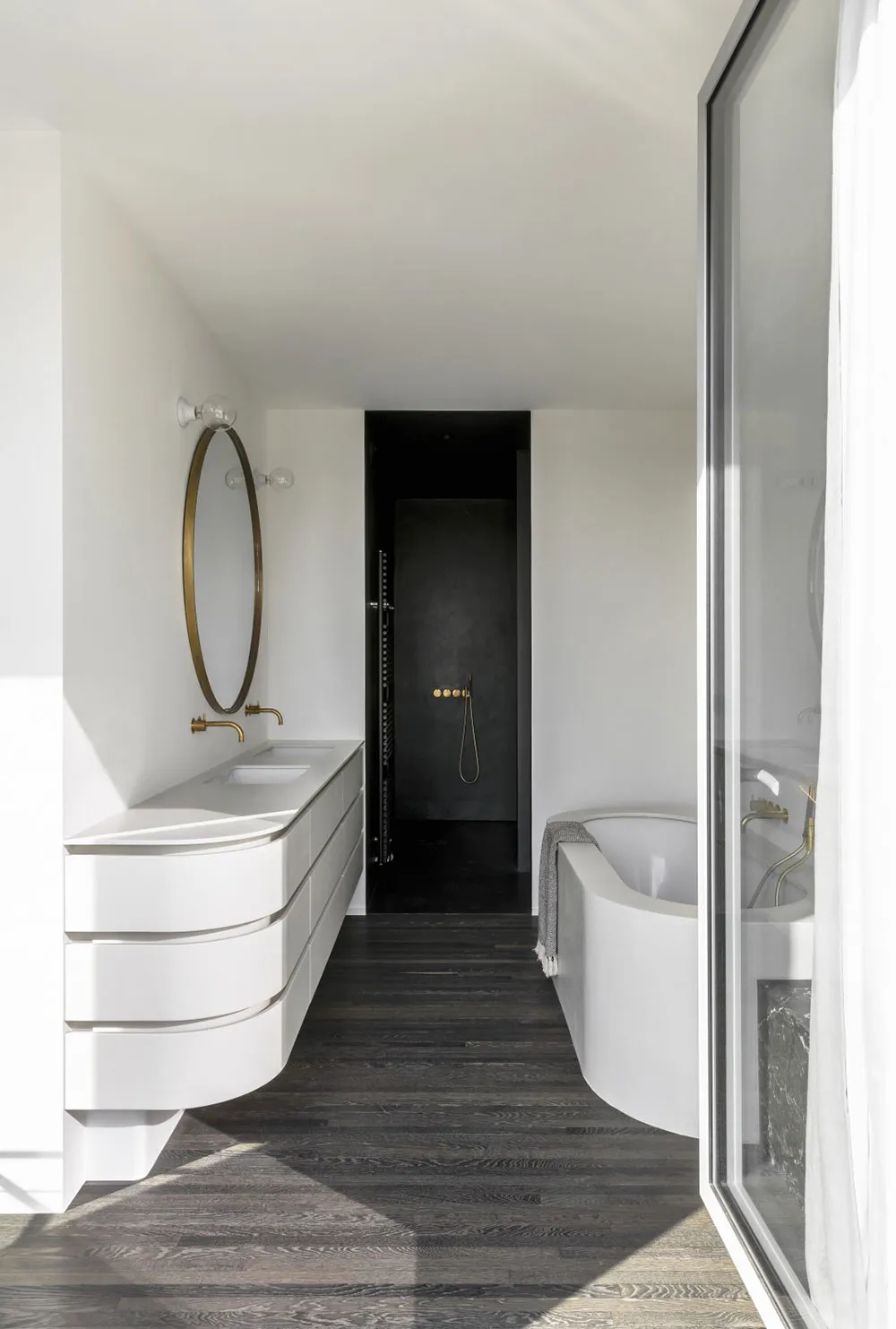 A modern bathroom with white marble countertops and black concrete walls.