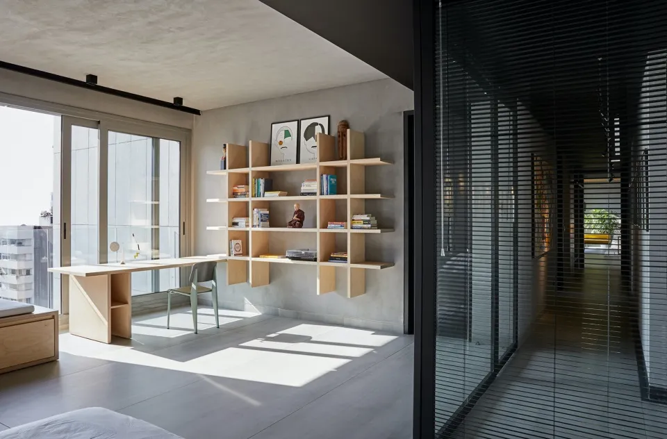 A modern office with a floating wooden shelf and a light wooden desk.