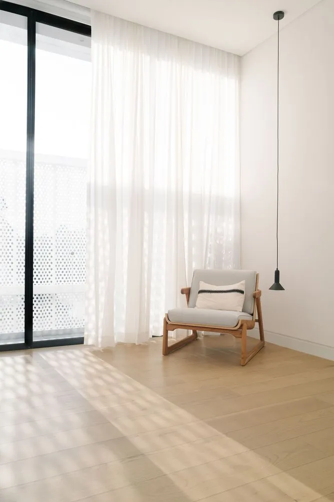 A minimalist living room with a wooden floor and fabric furniture.