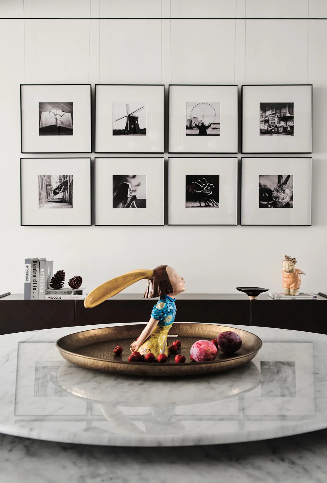 A modern interior featuring decorative art pieces and a metallic relish dish filled with colorful fruits.