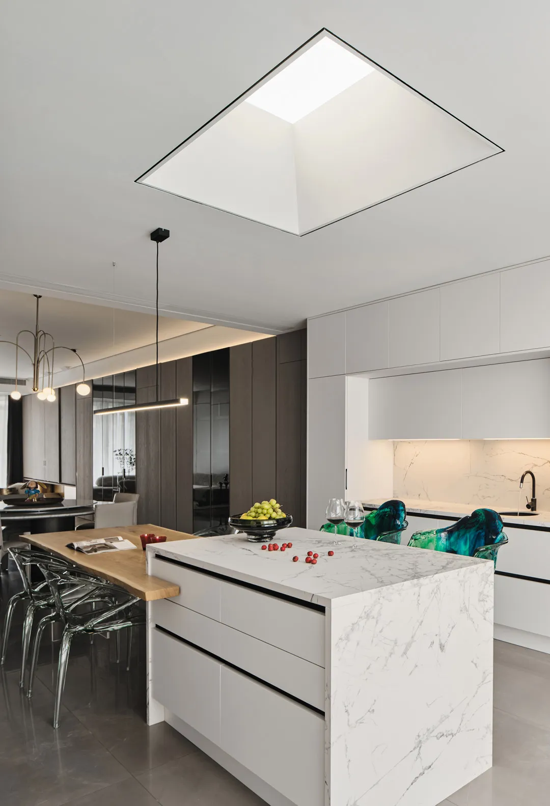 Modern residential kitchen featuring white marble countertops, glass cabinets, and wooden island.