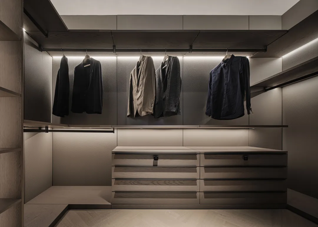 A modern wardrobe with hanging clothes and drawers in a minimalist design.